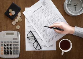 meja diatasnya terletak kopi, uang, kalkulator, dan tangan sedang menghitung keuntungan investasi di SBR014