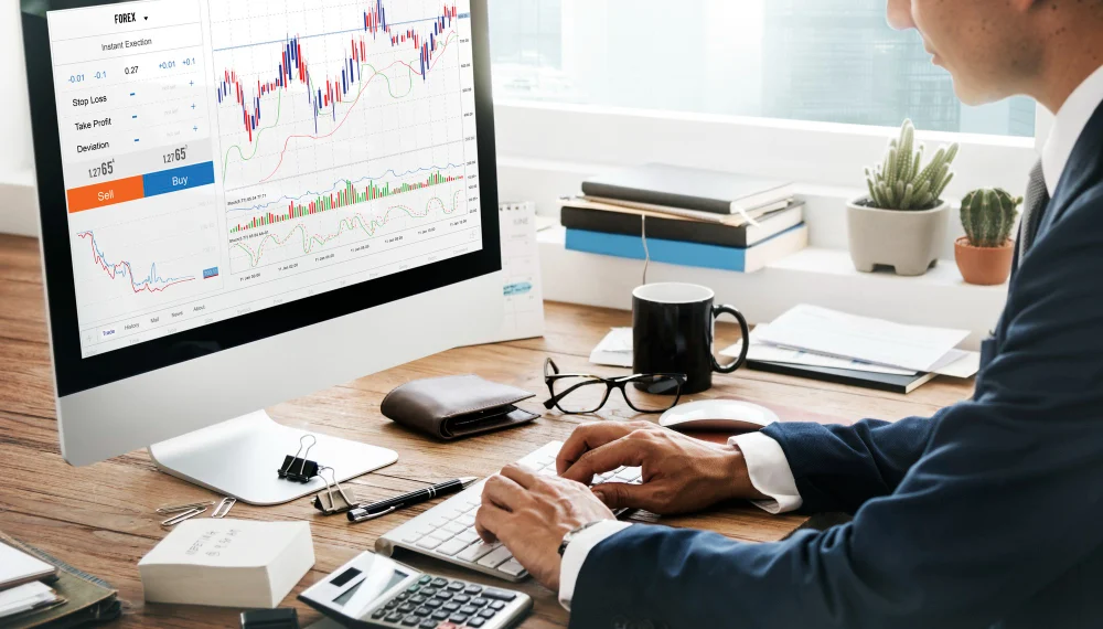 Seorang pria memakai jas sedang duduk di depan komputer menganalisis Sucorinvest Money Market Fund